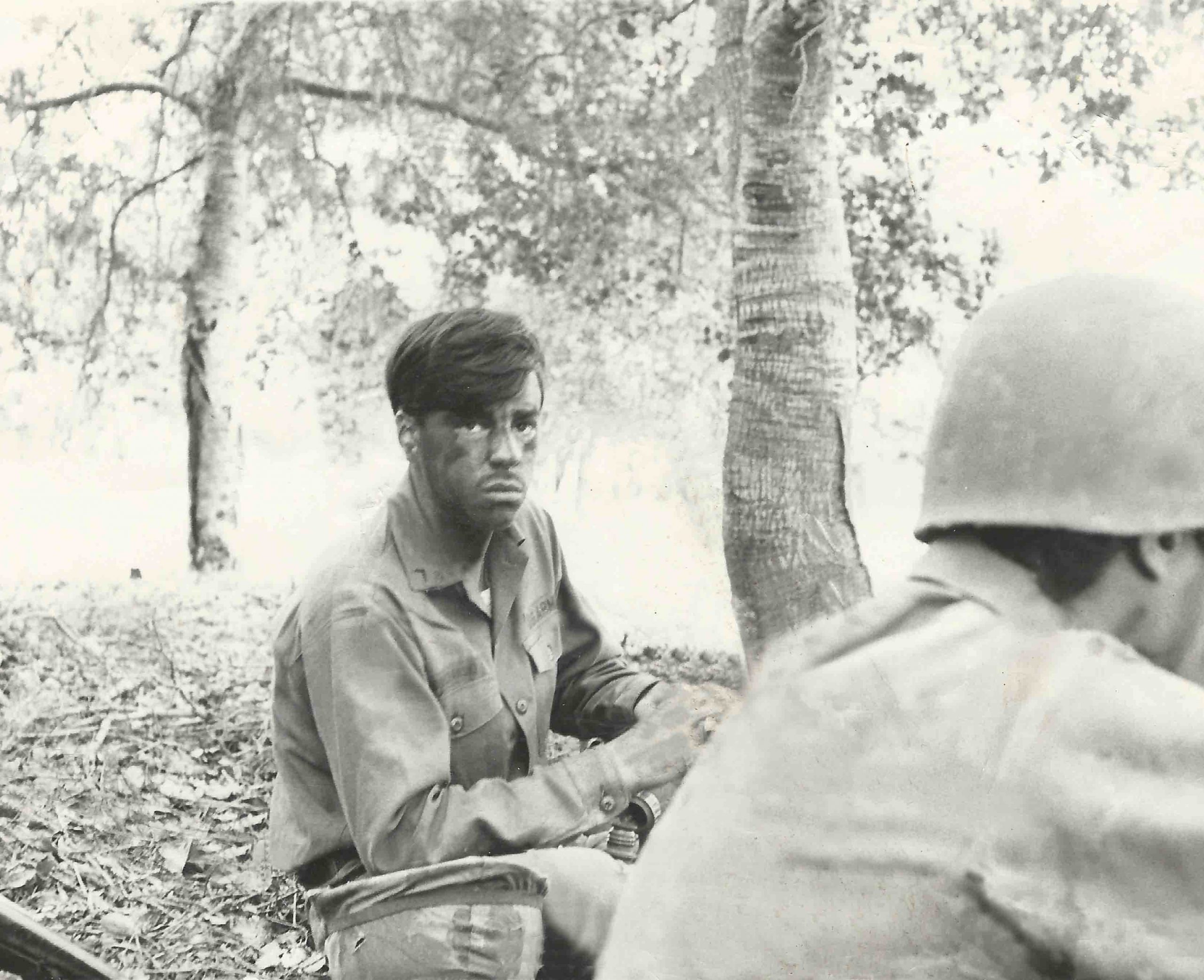 boise photographer dad in the army sitting in the forest with face painted looking serious with another army man in front.  cool black and white photo