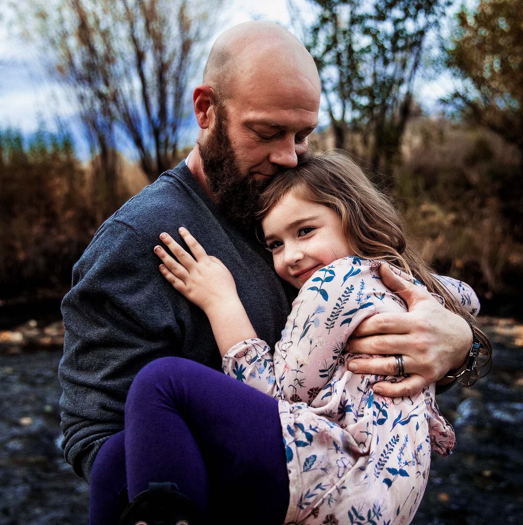boise-best-photographer-dad-with-beard-and-bald-holding-daughter-with-curly-hair-and-pink-top-smiling-and-hugging-daddy