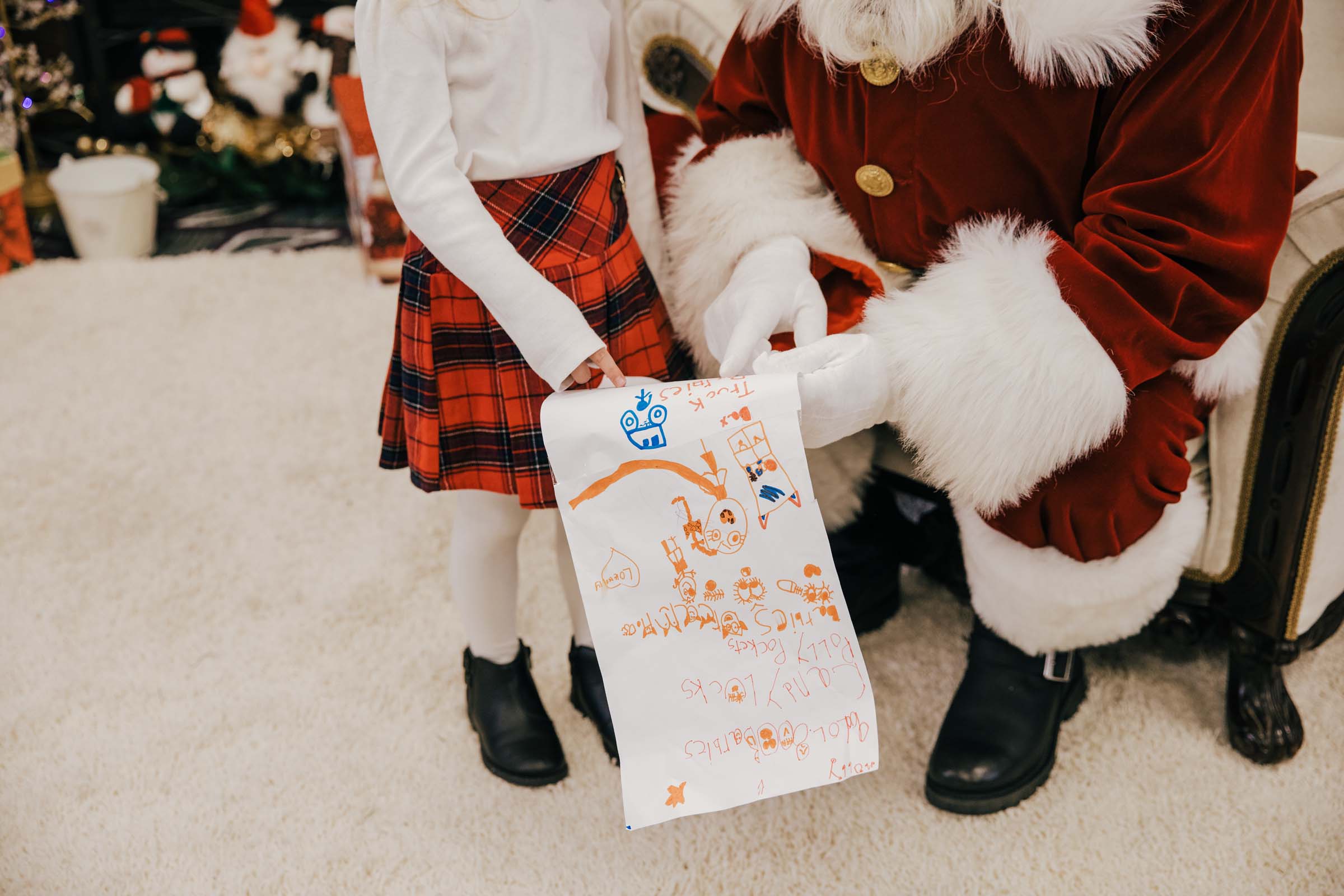 Little girl showing Santa her list that she drew with colored markers