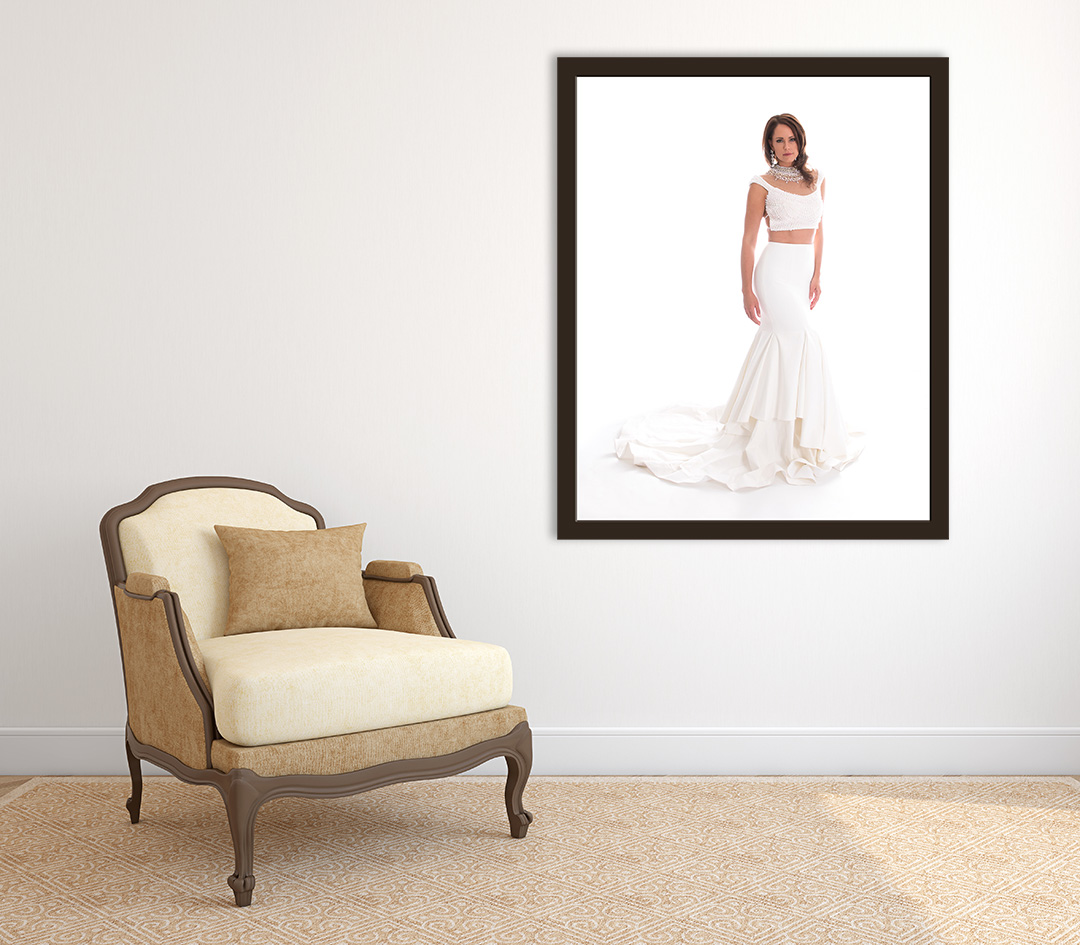 Beautiful framed print of a woman in a white dress two piece hanging on a wall with a beige arm chair next to the wall