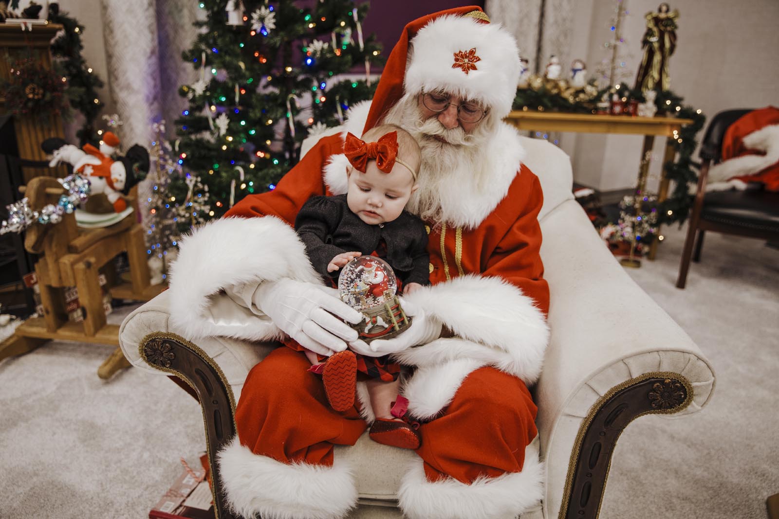 Boise Santa Pictures little baby girl sitting in Santa's lap looking at a snow globe