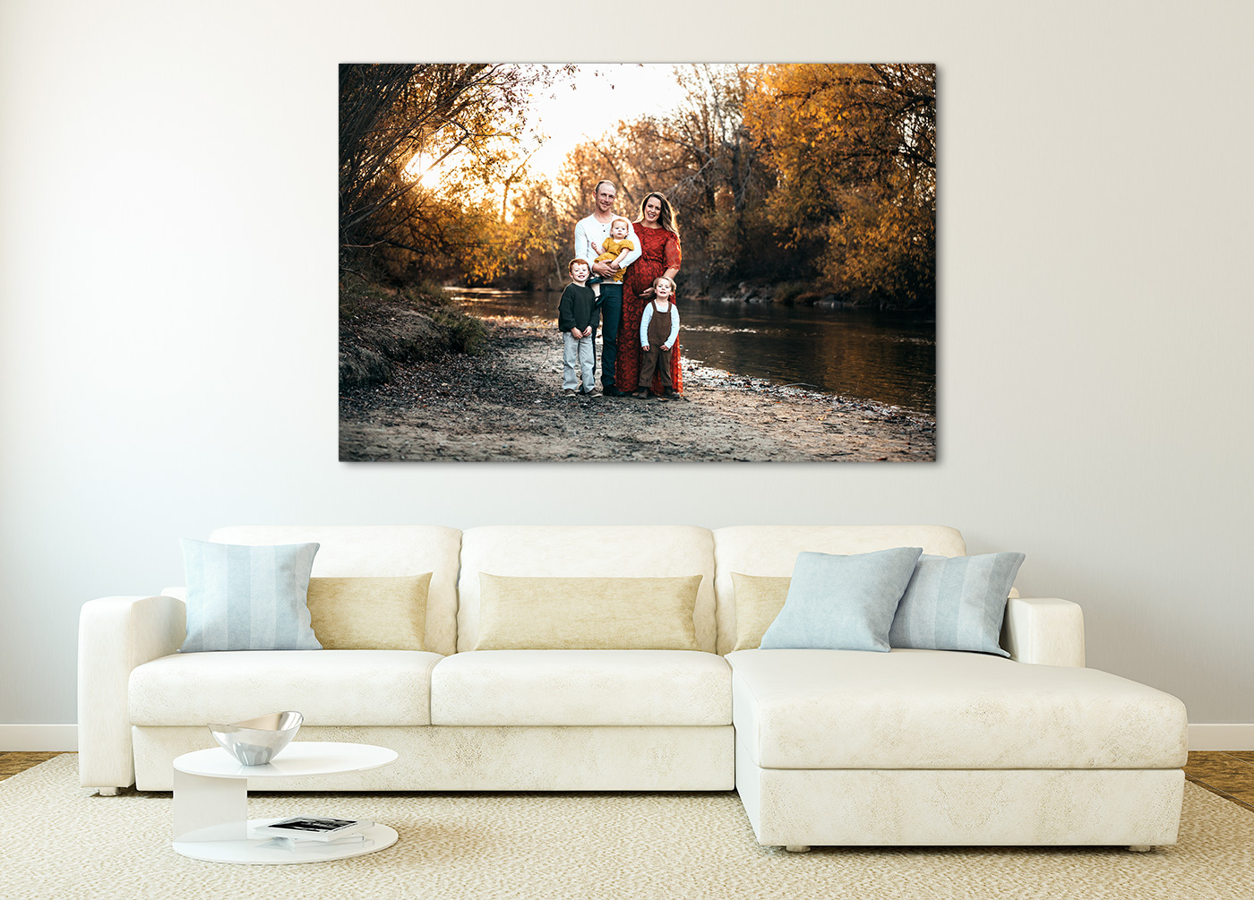 Beautiful living room with cream couch with a large metal print above it of a family of five standing on a river