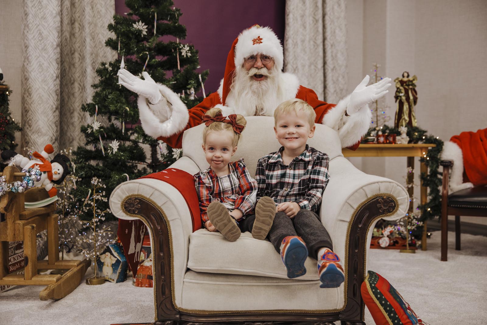 boise santa pics santa standing behind chair with brother and sister sitting in it smiling